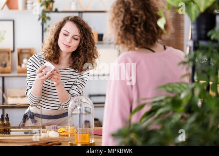 Woman selling organic skincare products in a small, local shop Stock Photo