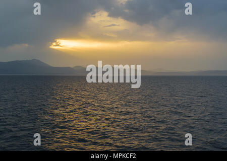 Sunset sunlight breaking through cloud seascape Stock Photo