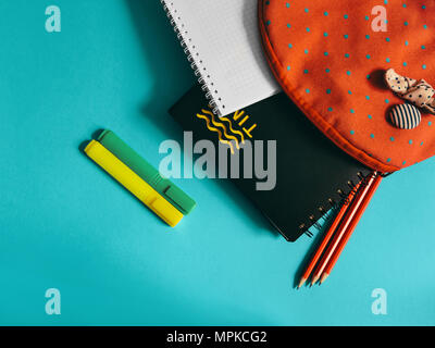 School supplies photo A pink backpack with notebooks, markers and pensils is lying on the blue desk Stock Photo