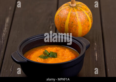 Pumpkin soup and small pumpkins on a wooden table. Stock Photo