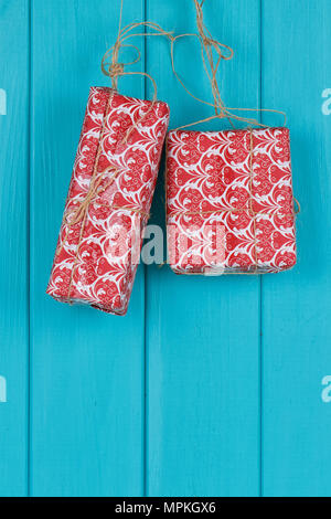 Christmas background of red apresents Christmas decorations hanging on rope in front of blue wooden background. Stock Photo