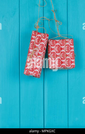 Christmas background of red apresents Christmas decorations hanging on rope in front of blue wooden background. Stock Photo
