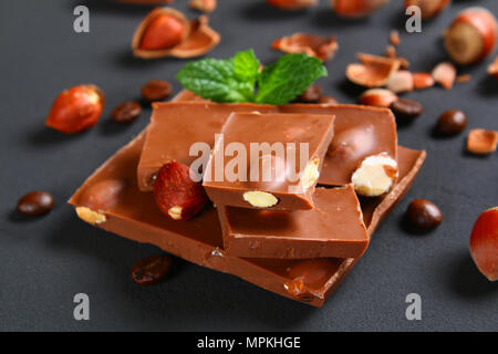 Chocolate with hazelnuts, mint and grains of coffee on a dark gray table Stock Photo
