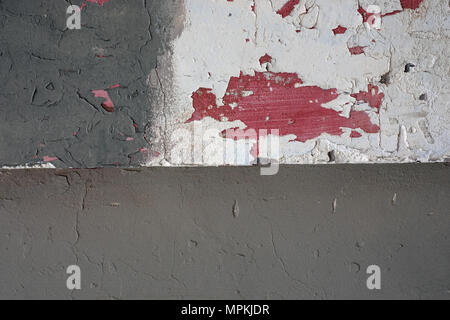 Grunge background is an old wall with plaster white and gray color, in some places the paint falls off and from under it visible spots are red, below  Stock Photo