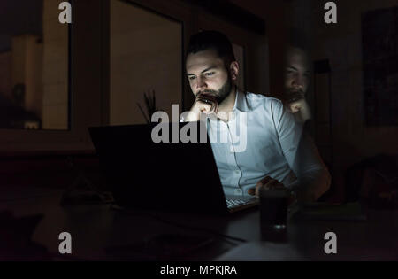 Businessman working on laptop in office at night Stock Photo