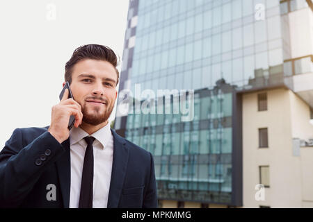 Businessman speaks on the phone outdoors Stock Photo