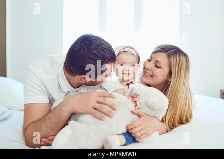 Happy family lying on bed in bedroom Stock Photo