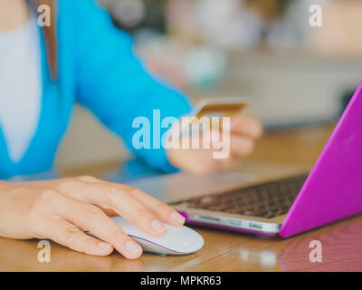 Pretty Young womans hands holding a credit card and using tablet, smartphone and laptop computer for online shopping. Online payment. Female working o Stock Photo