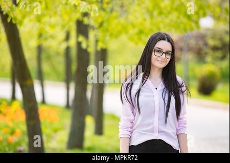 Outdoors portrait of beautiful young brunette girl looking at camera. Stock Photo