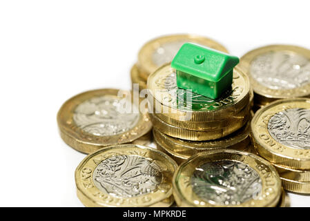 Macro close up of a Minature house resting on new pound coins with a white background Stock Photo