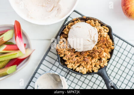 Homemade cooked rhubarb and apple crumble with oatmeal and vanilla ice cream in the iron pans Stock Photo