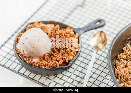 Homemade cooked rhubarb and apple crumble with oatmeal and vanilla ice cream in the iron pans Stock Photo