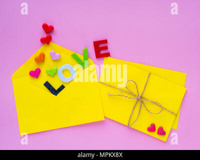 love letter concept. Opened envelope and many felt hearts. colorful of hearts with LOVE text on pink background. Stock Photo