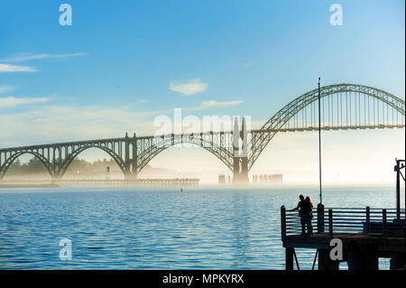 Newport,Oregon,USA - January 25, 2015:  Silhouette of a couple standing at end of pier gazing at the view of the Yaquina Bay Bridge in Newport, on th Stock Photo