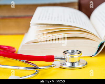 Stack of books and a stethoscope on yellow table background Stock Photo