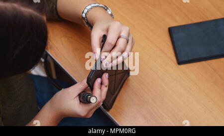Tanner grinds edges of leather purse. Handmade. Workflow in workshop. Shooting close-up. Stock Photo
