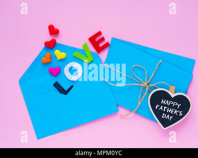 Happy Father's day love letter concept. Opened envelope and many felt hearts. colorful of hearts with LOVE text on pink background. Stock Photo