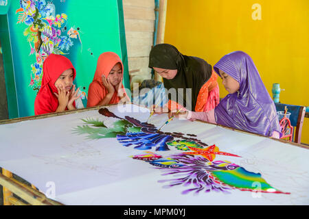 Krabi, Thailand - May 2, 2015: Cute Muslim girls wearing black and purple hijab painting pattern on Batik fabric in her home in Krabi, Thailand Stock Photo