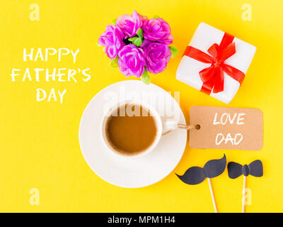 Father's day concept. Happy Father's Day and LOVE DAD message with pink flower, coffee cup, white gift and black Mustache on yellow background Stock Photo