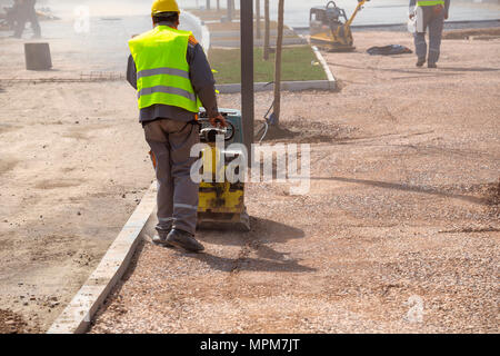 Construction worker compacting soil using compactor. Work with tamping ...