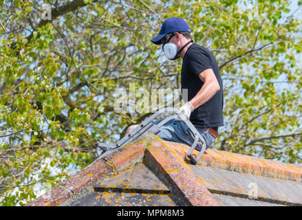 Man spraying a roof while wearing a protective respirator mask, in the UK. Stock Photo