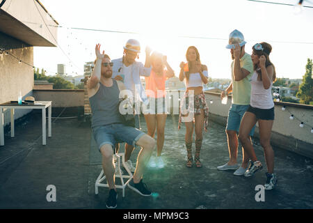 Group of happy friends having party on rooftop Stock Photo