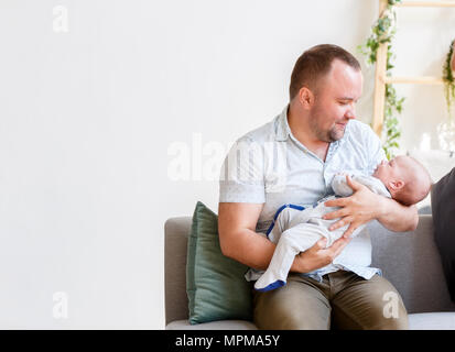 Photo of young father with newborn son sitting on sofa Stock Photo
