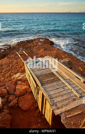 Traditional boathouse by the sea near Cala Saona with Es Vedrá islet and Ibiza island in the distance from Formentera (Balearic Islands, Spain) Stock Photo