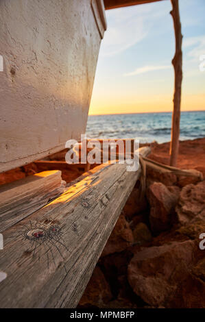 Boat at traditional wood boathouse stand with drawings by the sea at sunset at Caló d’en Trull near Cala Saona in Formentera (Balearic Islands, Spain) Stock Photo