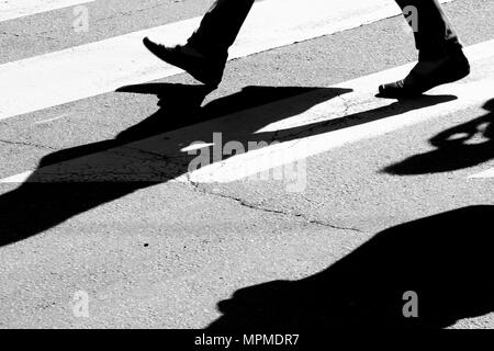 Blurry city street zebra crossing with walking pedestrians silhouettes  and  shadows in black and white high contrast Stock Photo