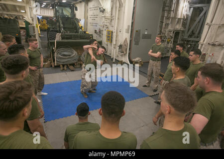 USS SOMERSET, At Sea (March 27, 2017) U.S. Marine Sgt. Scott Ingram, a light armored vehicle Marine, Light Armored Reconnaissance Company, Battalion Landing Team 1st Bn., 4th Marines, 11th Marine Expeditionary Unit (MEU), demonstrates the shoulder throw technique during a Marine Corps Martial Arts Program (MCMAP) training session aboard USS Somerset (LPD 25), March 27. During MCMAP, Marines learn essential combat skills such as how to employ weapons of opportunity, proper detainee handling procedures, and varying counter strike techniques. The 11th MEU/Makin Island Amphibious Ready Group is cu Stock Photo