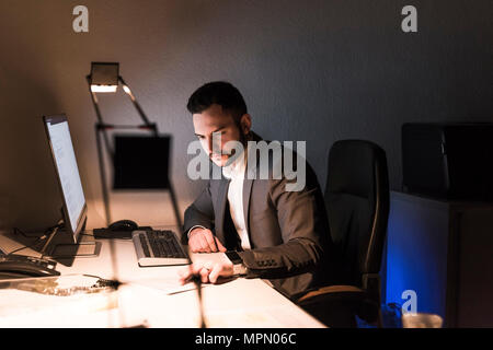 Businessman working on desk in office at night Stock Photo