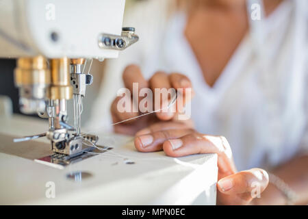 Close-up of woman using sewing machine Stock Photo