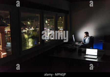 Businessman working on computer in office at night Stock Photo