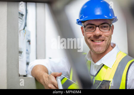 Portrait of smiling electrician at fuse box Stock Photo