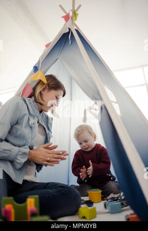 Mother playing with her son in a tent at home Stock Photo