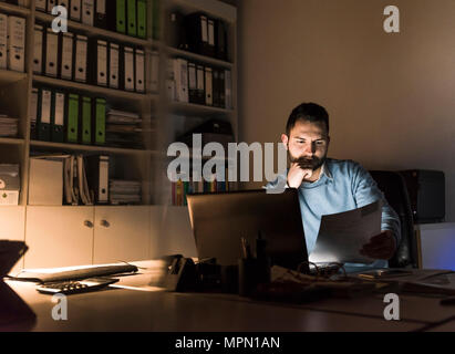Businessman working at desk in office at night Stock Photo