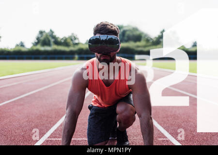 Athlete in starting position on tartan track wearing VR glasses surrounded by numbers Stock Photo