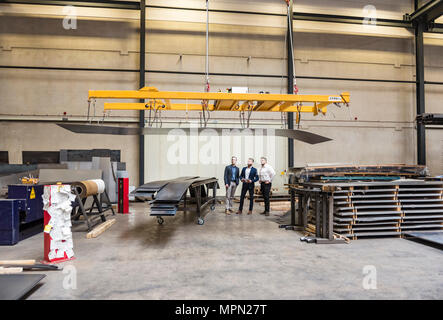 Three men standing on factory shop floor Stock Photo