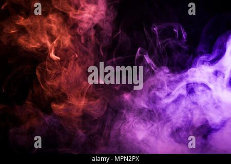 Dense multicolored smoke of  pink and red colors on a black isolated background. Background of smoke vape Stock Photo