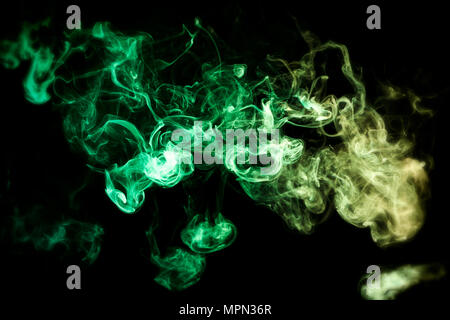 Dense multicolored smoke of   green and yellow colors on a black isolated background. Stock Photo