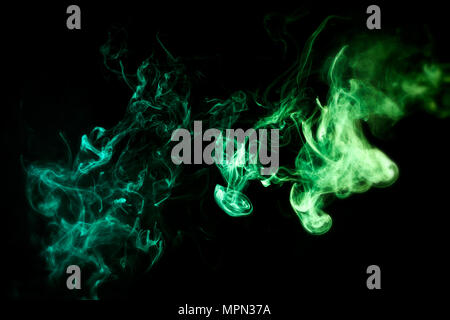 Dense multicolored smoke of   green and yellow colors on a black isolated background. Stock Photo