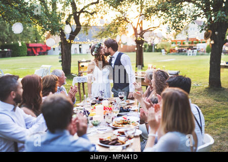 Bride and groom with guests at wedding reception outside in the backyard. Stock Photo
