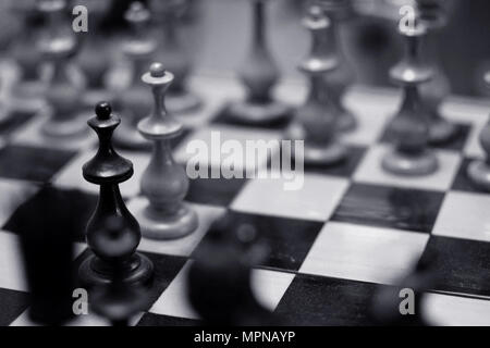 The opening of the chess game with the move of the white king pawn e2-e4,  copy space on a black background. A man hand with a chess piece in a board g
