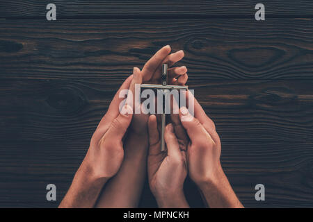 cropped image of woman and man holding cross in hands Stock Photo