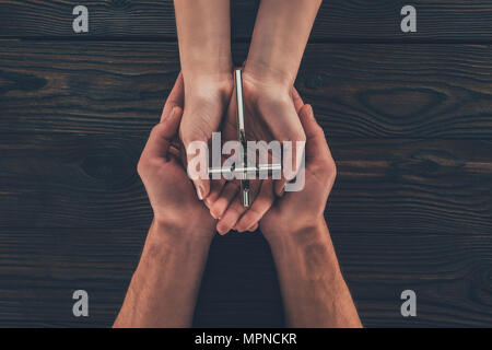 cropped image of woman and man holding christian cross in hands Stock Photo