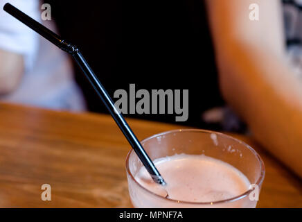 Fresh grapefruit juice and black long straw in the glass on a wooden table .Copyspace top. Stock Photo