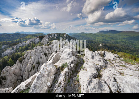 Hiking path through the karst wilderness of eroded limestone peaks surrounded by forest, in Bijele stijene natural reserve, Croatia Stock Photo