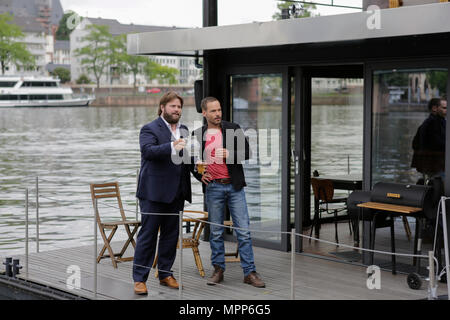 Frankfurt, Germany. 24th May 2018. Actors Antoine Monot, Jr. (left) and Wanja Mues (right) pose on the terrace of the houseboat that is owned by Mues' character Leo in the TV show with two glasses of cider and a Bembel (a local type of stoneware jug, used for cider). 4 new episodes of the relaunch of the long running TV series 'Ein Fall fuer zwei’ (A case for two) are being filmed in Frankfurt for the German state TV broadcaster ZDF (Zweites Deutsches Fernsehen). It stars Antoine Monot, Jr. as defence attorney Benjamin ‘Benni’ Hornberg and Wanja Mues as private investigator Leo Oswald. The epi Stock Photo