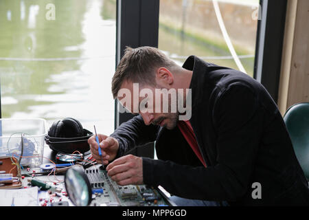 Frankfurt, Germany. 24th May 2018. Actors Wanja Mues poses on the desk in the houseboat that is owned by Mues' character Leo in the TV show, working on a computer circuit board. 4 new episodes of the relaunch of the long running TV series 'Ein Fall fuer zwei’ (A case for two) are being filmed in Frankfurt for the German state TV broadcaster ZDF (Zweites Deutsches Fernsehen). It stars Antoine Monot, Jr. as defence attorney Benjamin ‘Benni’ Hornberg and Wanja Mues as private investigator Leo Oswald. The episodes are directed by Thomas Nennstiel. The episodes are set to air in October. Stock Photo